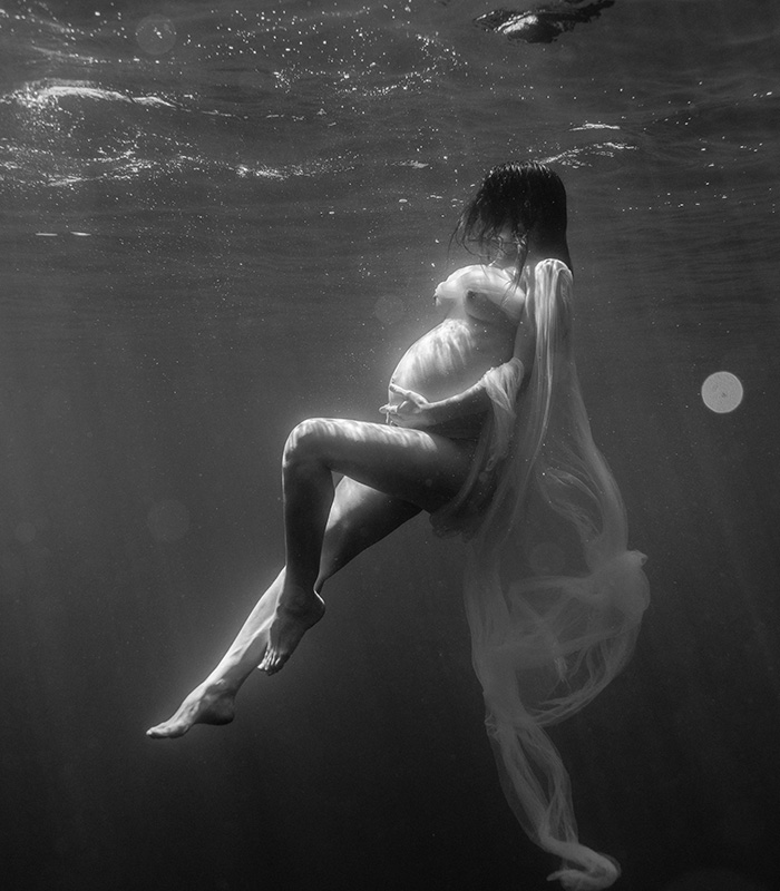 Femme enceinte en séance photo grossesse underwater en mer, noir et blanc